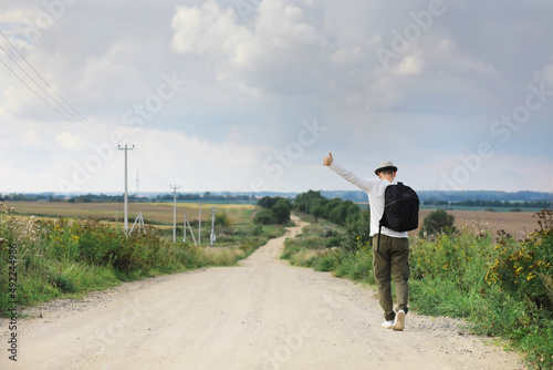 A man walks along a country road. Hitchhiker around the country. A man stops a passing car on the road.
