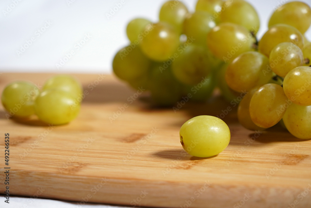 Green grapes with white background on wooden board. Green grapes with white background on wooden board.