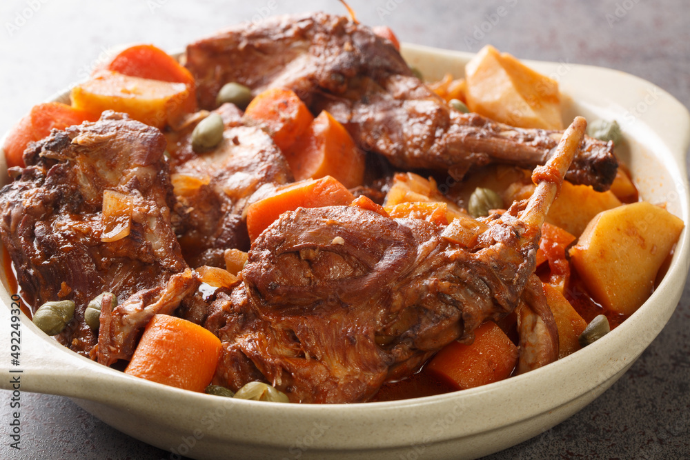 Rabbit stewed in red wine with vegetables and garlic close-up in a saucepan. horizontal Rabbit stewed in red wine with vegetables and garlic close-up in a saucepan. horizontal