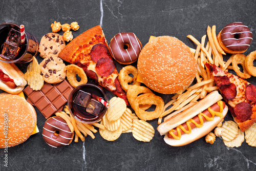 Fotografi Junk food table scene scattered over a dark background