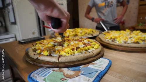 Cutting breakfast pizza with a pizza wheel close-up