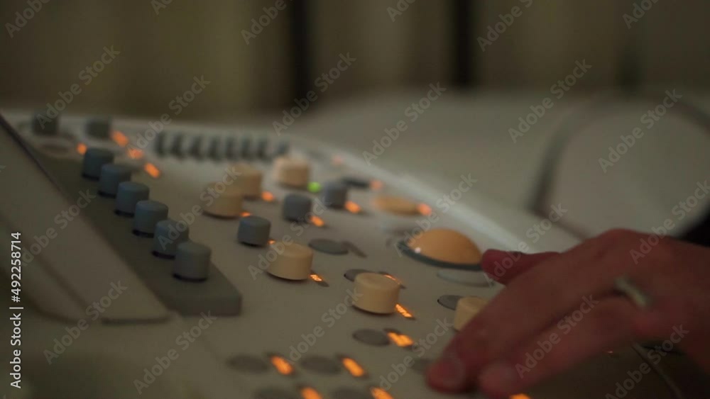 Person touching dials on medical equipment with switches and lights Person touching dials on medical equipment with switches and lights