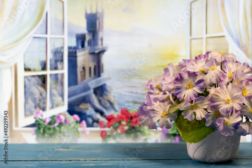 Blue flowers in a vase on the background of an open window overlooking the sea
