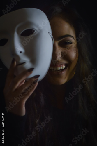 portrait of a beautiful girl with long hair laughing happily taking off her mask - being real and not so serious
