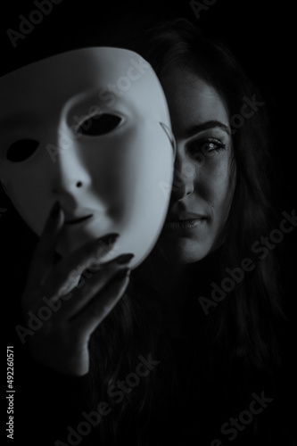 Being authentic and true concept - Black and white portrait of a beautiful young woman with long hair taking off her mask