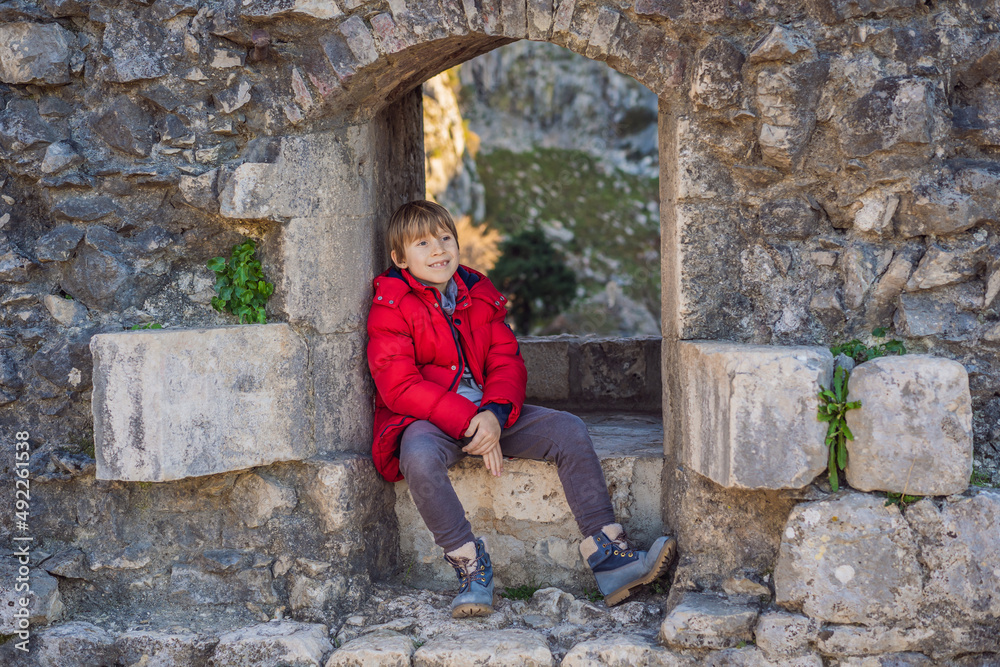 Young tourist boy enjoying a view of Kotor Bay, Montenegro. Kotor Old Town Ladder of Kotor Fortress Hiking Trail. Aerial drone view
