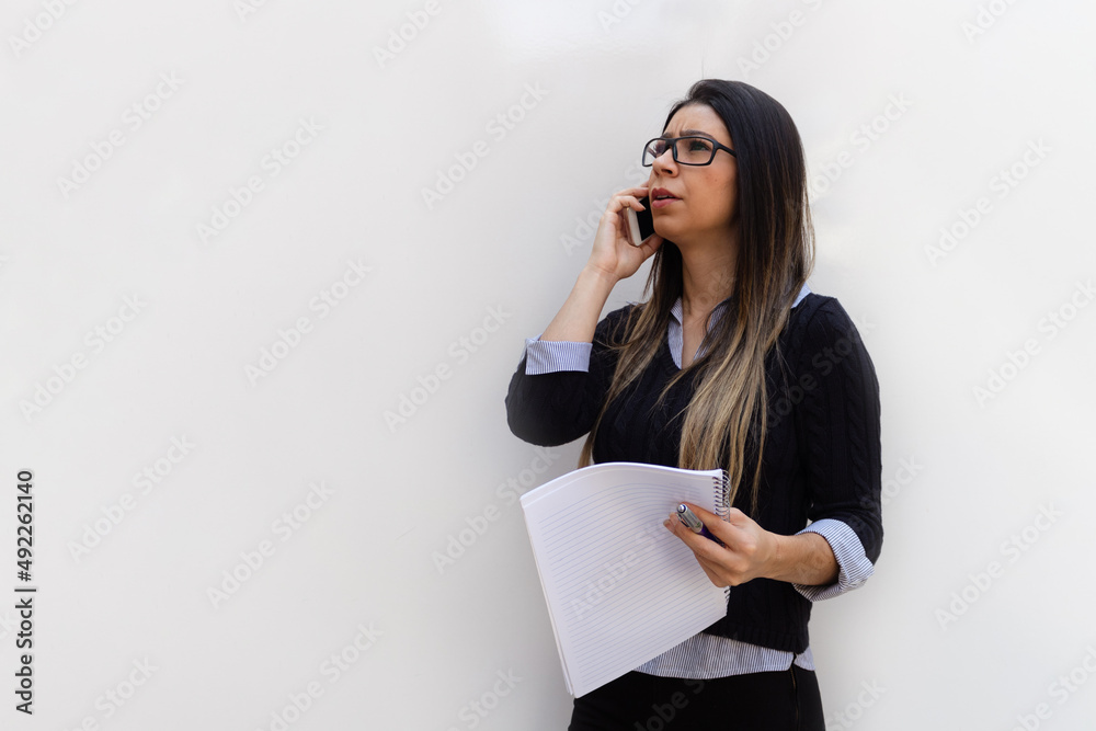 Portrait of a Young Brunette Business Woman holding a mobile, pencil and notebook Isolated on White Background. Portrait of a Young Brunette Business Woman holding a mobile, pencil and notebook Isolated on White Background.