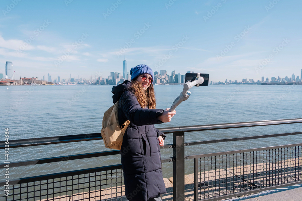 Young woman recording a vlog with her mobile and a gimbal in New York city. Travel concept. influencer concept. Happiness concept.