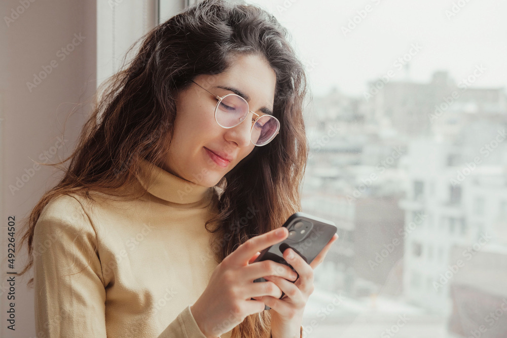 Close-up of a woman smiling while using her mobile. Technology concept. Close-up of a woman smiling while using her mobile. Technology concept.