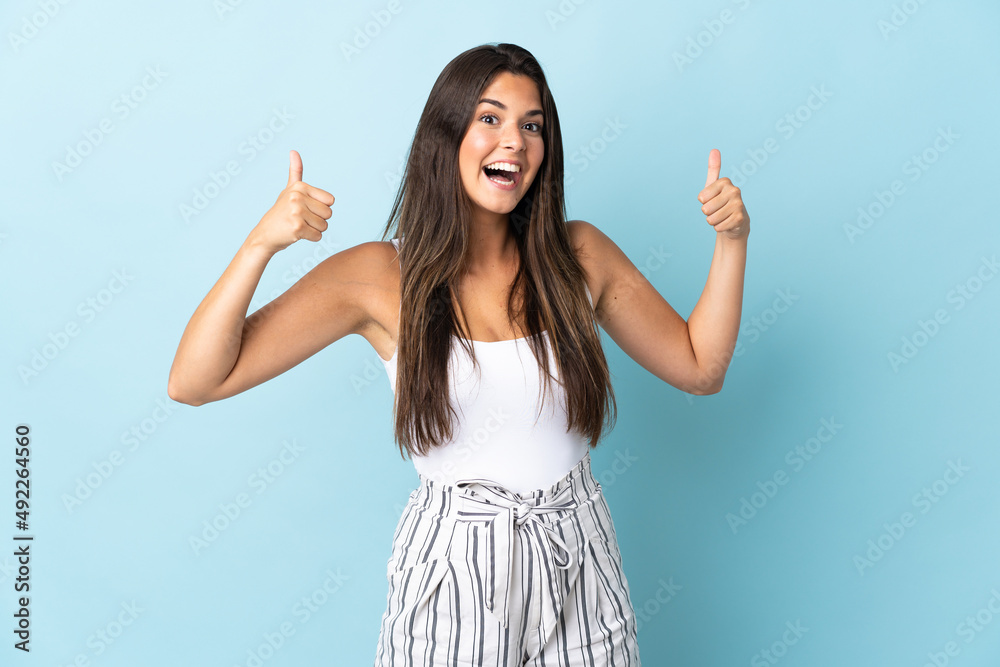 Young brazilian woman isolated on blue background giving a thumbs up gesture