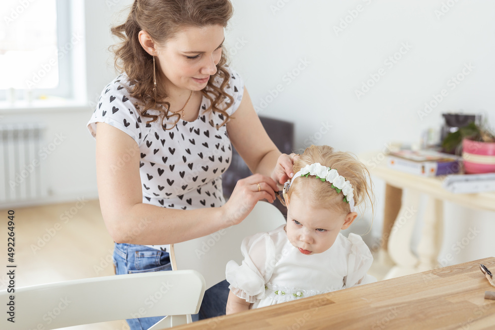 Mother helps to put on cochlear implant for her deaf little daughter. Hearing aid and deafness concept Mother helps to put on cochlear implant for her deaf little daughter. Hearing aid and deafness concept