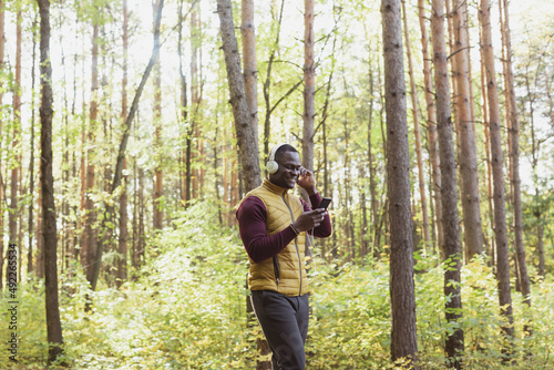 African american man listens music in spring park copy space and place for advertising. Gadget, app and streaming service concept