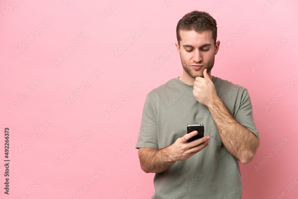 Young caucasian man isolated on pink background thinking and sending a message Young caucasian man isolated on pink background thinking and sending a message