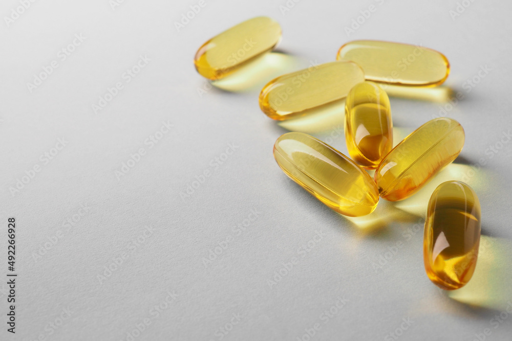 Fish oil. Yellow softgels lie on a white or light gray surface. Vitamins and a healthy lifestyle. Background or backdrop. Copy space on the left. Softgel close-up. Omega-3 fatty acids. Macro Fish oil. Yellow softgels lie on a white or light gray surface. Vitamins and a healthy lifestyle. Background or backdrop. Copy space on the left. Softgel close-up. Omega-3 fatty acids. Macro