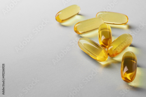 Fish oil. Yellow softgels lie on a white or light gray surface. Vitamins and a healthy lifestyle. Background or backdrop. Copy space on the left. Softgel close-up. Omega-3 fatty acids. Macro