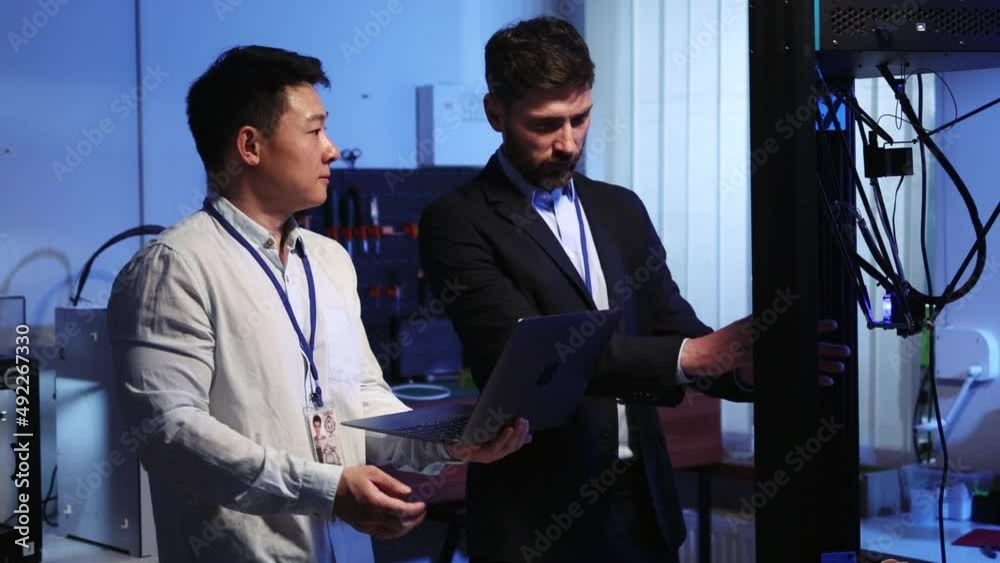 Asian lab engineer cooperating with caucasian employee explaining work