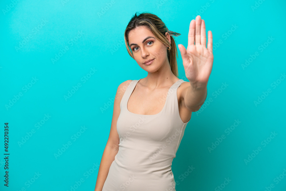 Fototapeta premium Young caucasian woman isolated on blue background making stop gesture