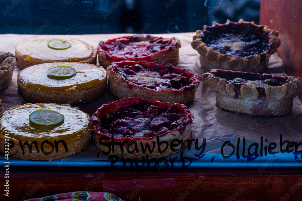 lemon and berry tartlets in rows inside display case with handwritten labels on glass at local farmer's market lemon and berry tartlets in rows inside display case with handwritten labels on glass at local farmer's market