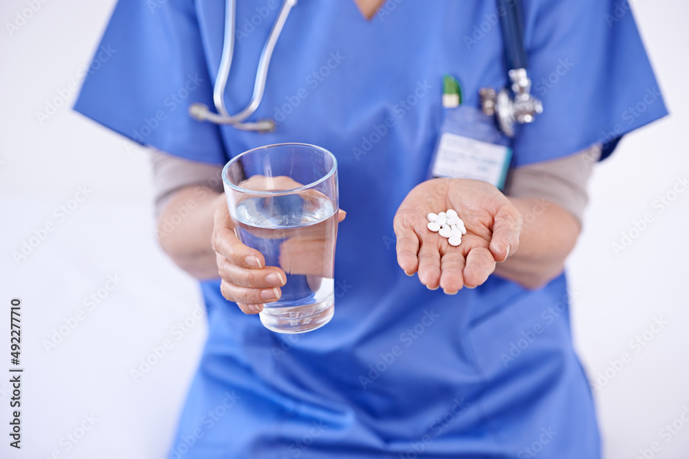 Heres your medication for the week. Shot of a female doctor holding medication and glass of water. Heres your medication for the week. Shot of a female doctor holding medication and glass of water.