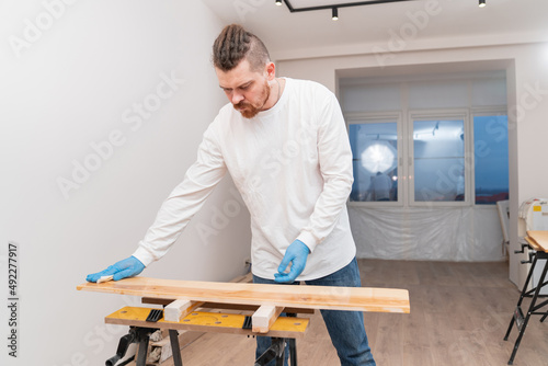the carpenter covers the wood with oil with a napkin.  © andrey