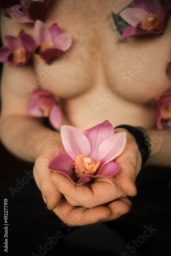 Handsome man holds orchid flower in hands. Fragile flower in strong male hands