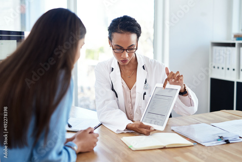 Less paper, more patient feedback. Shot of a young doctor using a digital tablet during a consultation with her patient.
