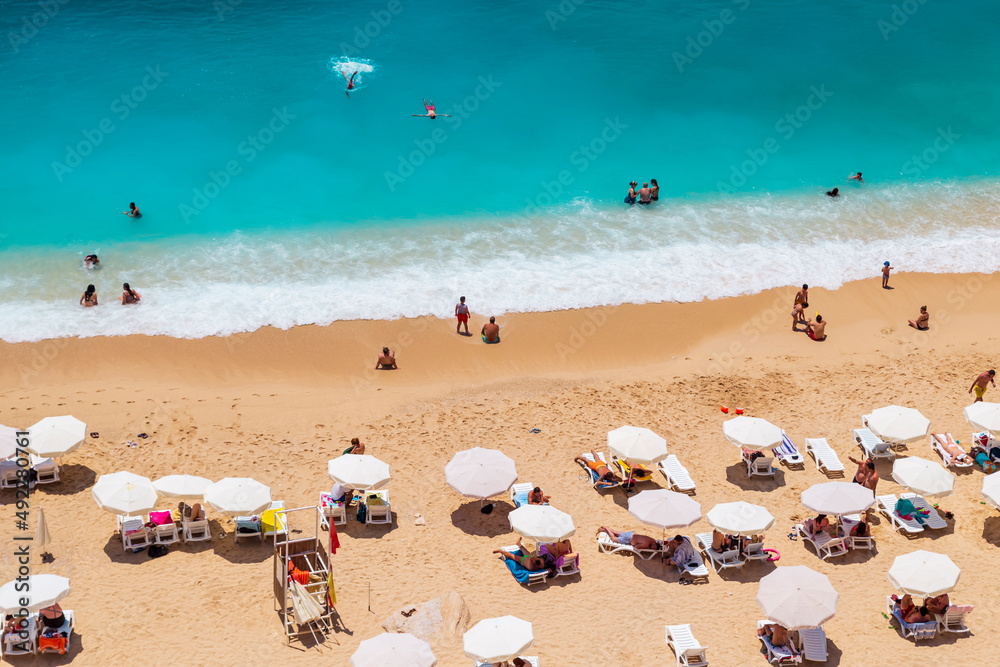Aerial View From Flying Drone Of People Crowd Relaxing On Beach. Swimming people in sea. Top view of Kaputas Beach between Kas and Kalkan Aerial View From Flying Drone Of People Crowd Relaxing On Beach. Swimming people in sea. Top view of Kaputas Beach between Kas and Kalkan