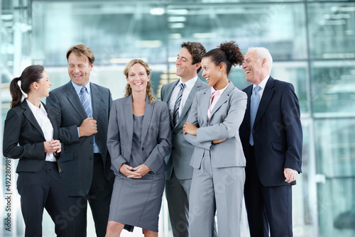 Supported by her proud team of coworkers. Positive group of businesspeople standing together and smiling while surrounding a coworker - portrait.