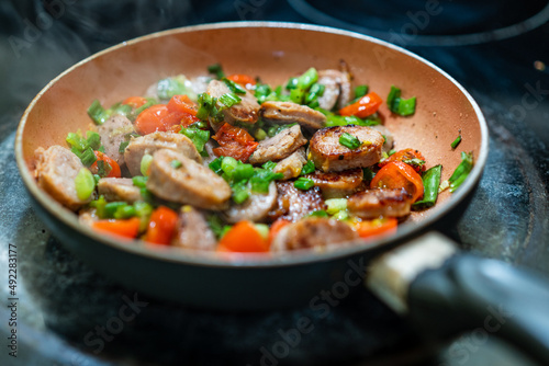 Sausage and vegetables frying in a pan.