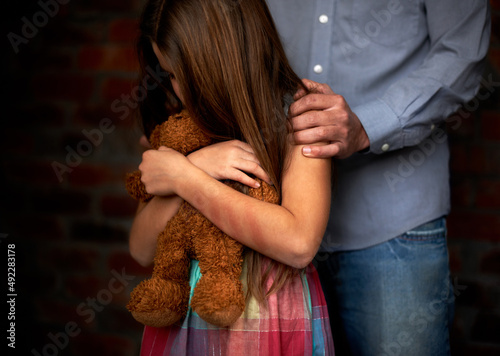 Innocence lost. Abused little girl with her abuser gripping her shoulder. photo