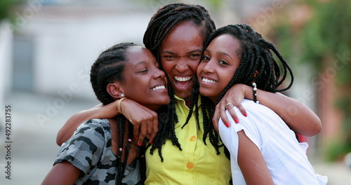 Funny mother hugging daughters outside. African black ethnicity family love and affection