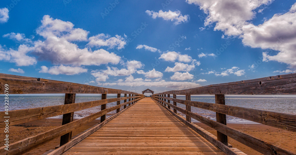 Tropical Pier Over Sea Against Sky In Kauai, HI Tropical Pier Over Sea Against Sky In Kauai, HI