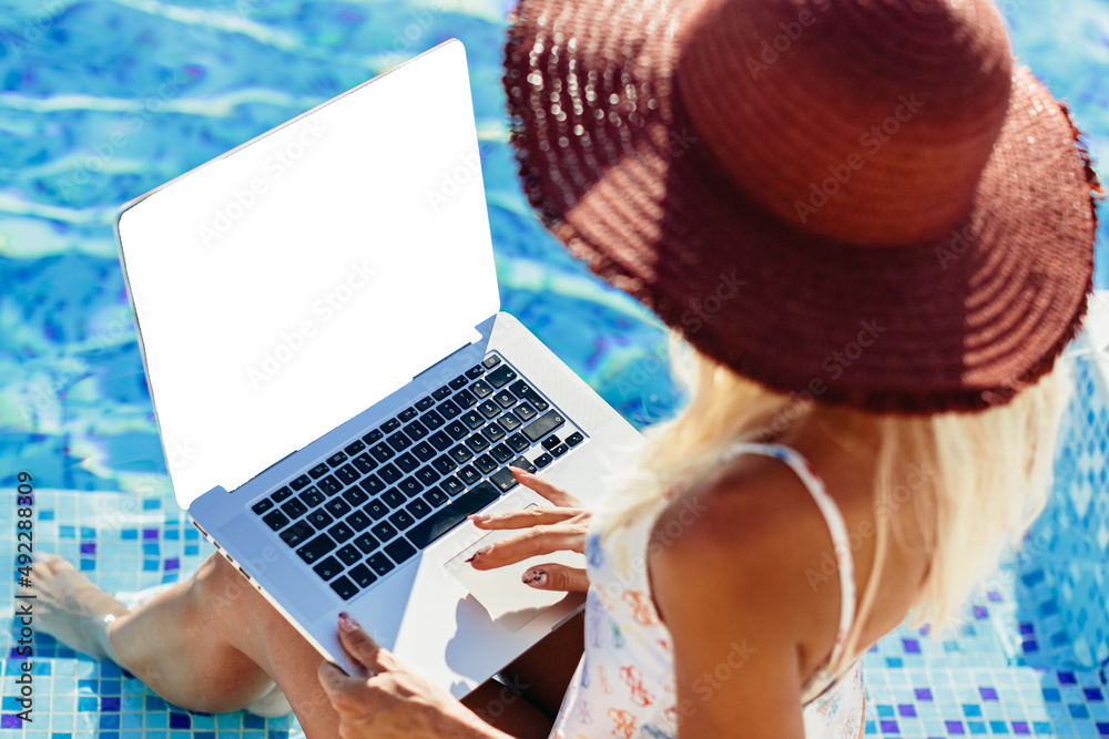 woman using laptop and work remotely near swimming pool. Sexy woman freelancer browsing notebook on self isolation quarantine at home pool outdoors. Mockup laptop screen