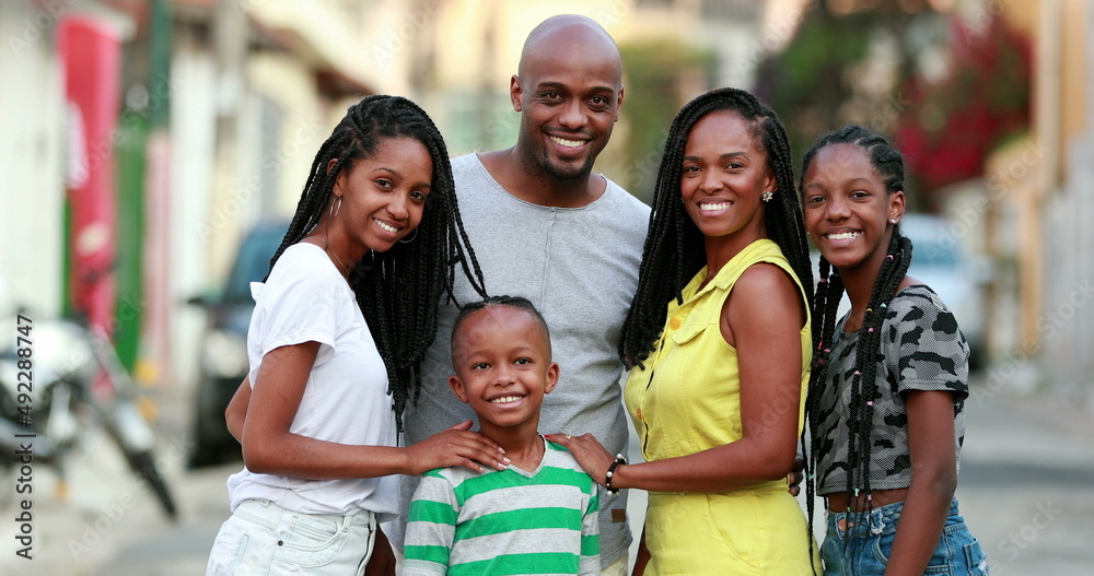 Fototapeta premium Beautiful black family smiling at camera. African parents and kids standing outdoors