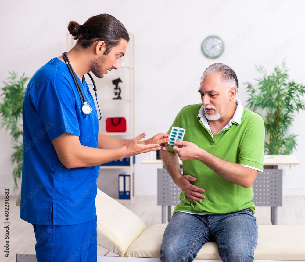 Obraz premium Old man visiting young male doctor gastroenterologist