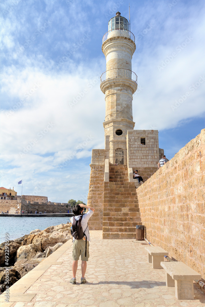 A Photographer taking a photo of The lighthouse of Chania, Crete, Greece.