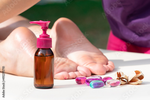 Massage of legs  female feet with bottle of oil. Close up photo of woman foot and therapist s hands of masseur massagist. Professional physiotherapist. Unrecognisable person is lying relaxing on table