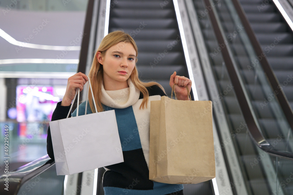 Portrait of happy positive cheerful teen teenager girl, young beautiful pretty woman is smiling in mall, shopping with bags. Shopaholic lady customer buying clothes in shop, store. Sale. Copy space