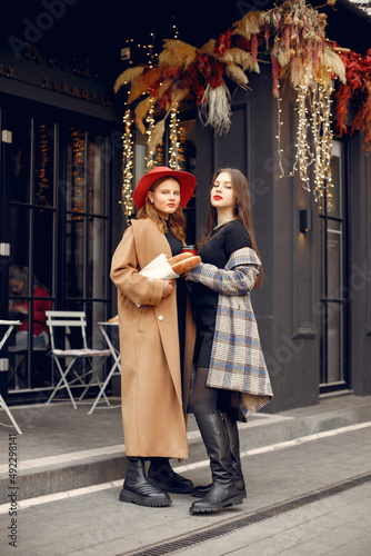 Two young girls standing near outdoor cafe holding a coffee and baguettes