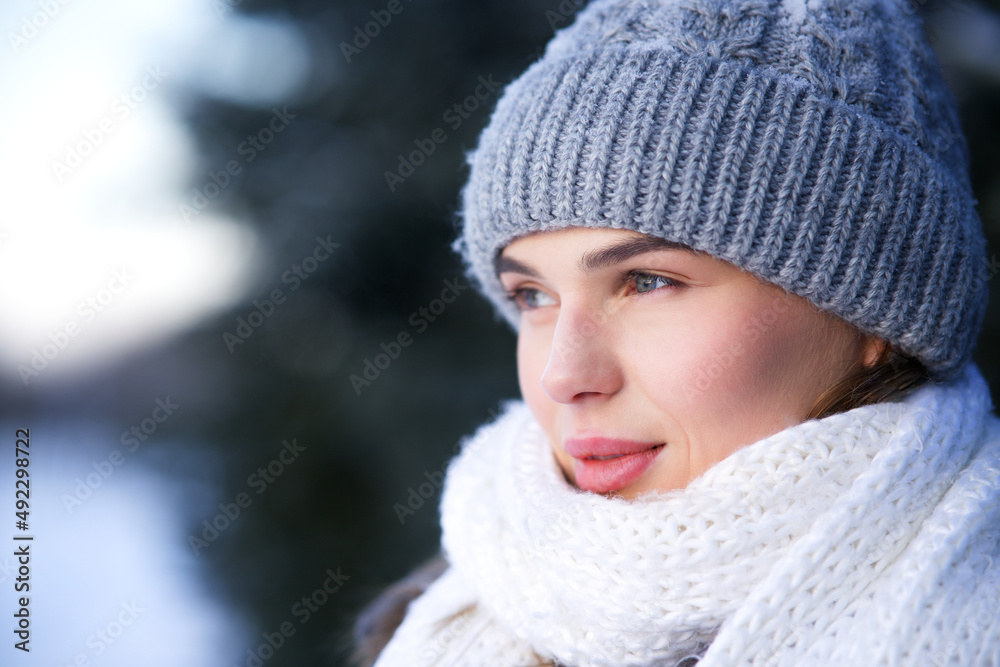 Close up beauty portrait of beautiful girl, pretty attractive woman in warm clothes knitted hat and white scarf is walking in winter snowy park at cold snow frosty day looking into distance. North Close up beauty portrait of beautiful girl, pretty attractive woman in warm clothes knitted hat and white scarf is walking in winter snowy park at cold snow frosty day looking into distance. North
