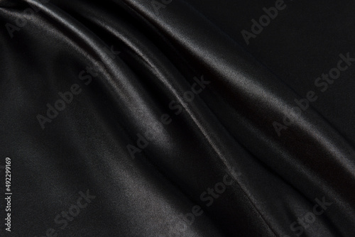 Abstract black silk fabric texture background. Creases of satin