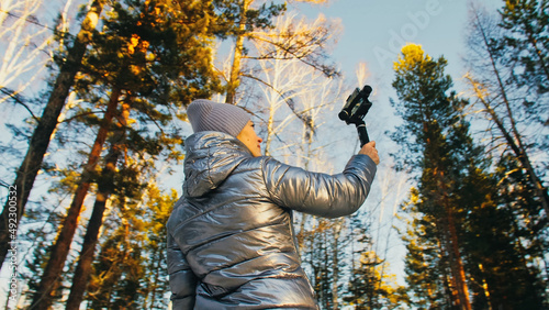 The Woman Professional Videographer Holding Smartphone on 3-axis Gimbal Stabilization Device in Winter. Pro Equipment Helps to Make High Quality Video on Phone. Cinematographer Operator. Slow Motion