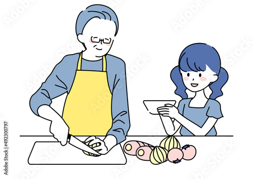 料理をするシニア男性とお手伝いする孫