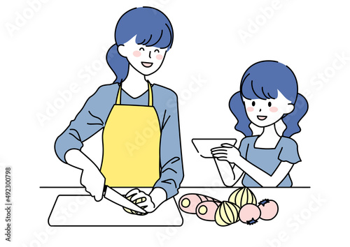 料理をする母親とお手伝いする娘