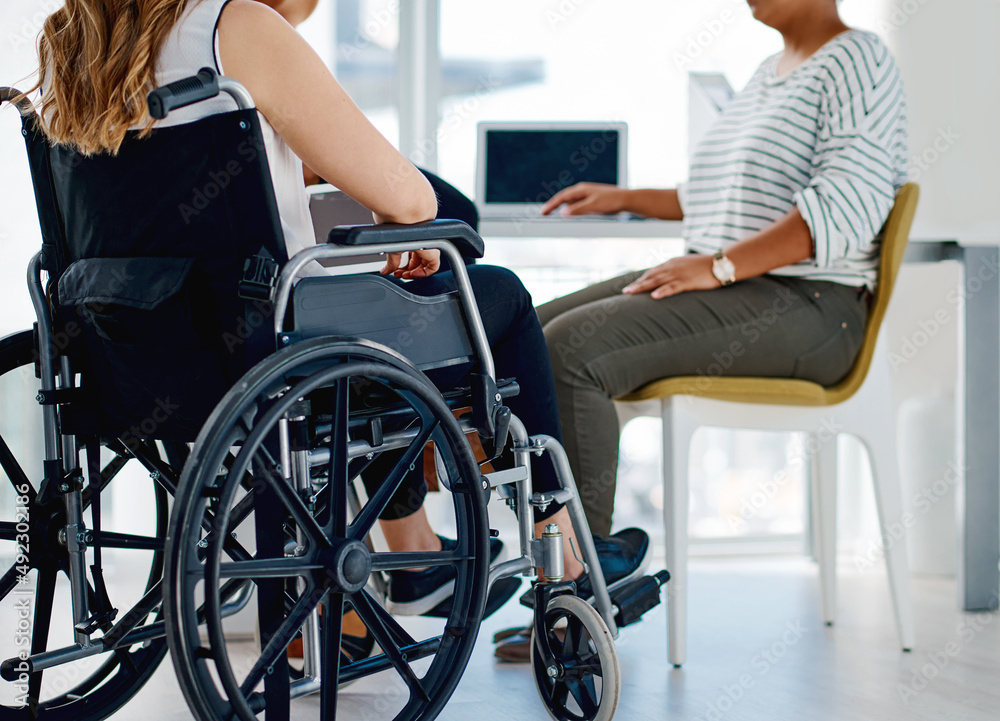 Obraz premium We all put in the same amount of work. Shot of a businesswoman with disabilities sitting with colleagues in the office.