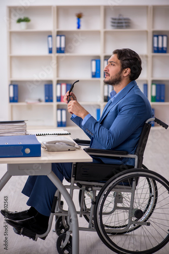 Young male employee in wheel-chair sitting in the office