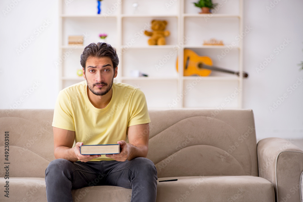 Young man reading book at home during pandemic