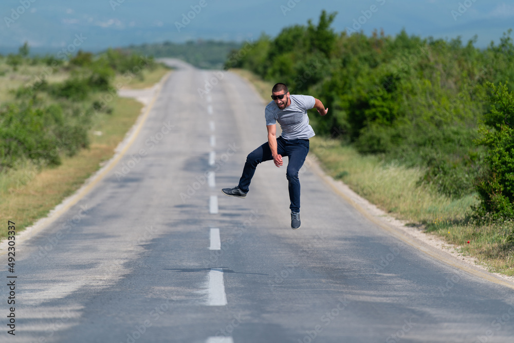 Muscular Man Jumping Outdoors at Highway