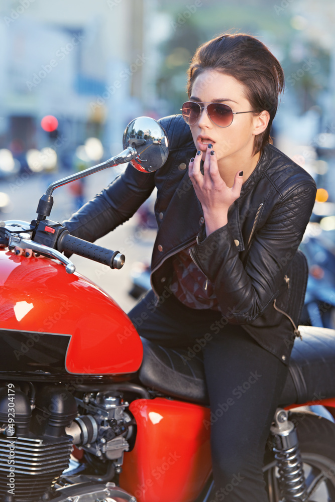 Looking good.... A beautiful young biker looking at herself in her bikes mirror. Looking good.... A beautiful young biker looking at herself in her bikes mirror.
