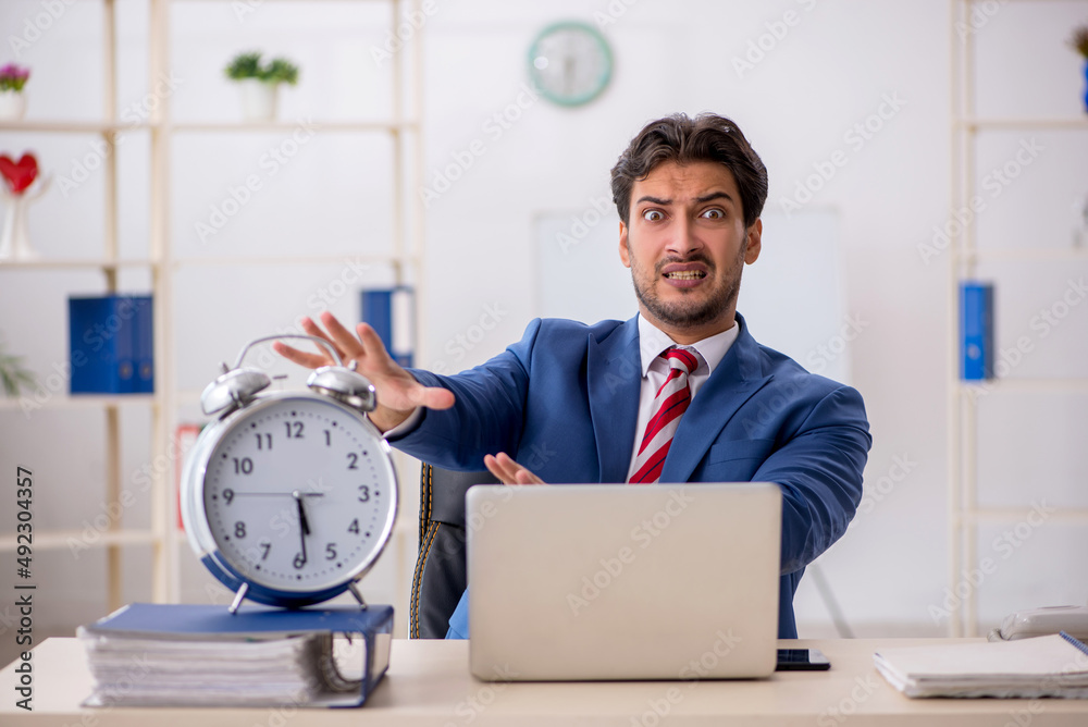 Young male employee in time management concept Young male employee in time management concept